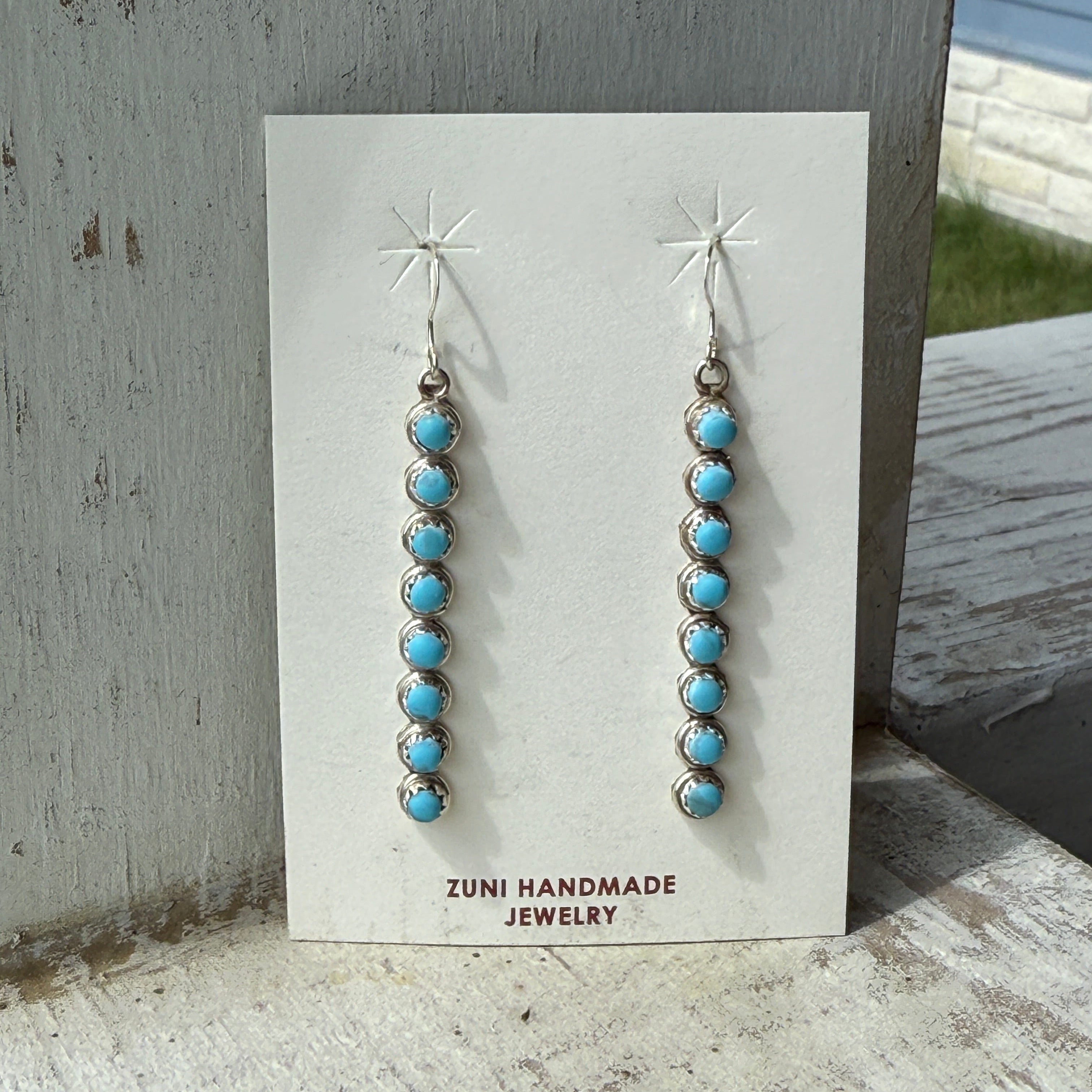 Pair of turquoise beaded earrings on a Zuni Handmade Jewelry card.