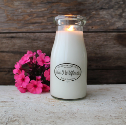 Glass bottle candle with a wooden background and pink flowers