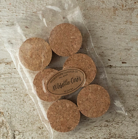 A set of six cork stoppers packaged in a clear plastic bag, designed to fit Milkhouse Milkbottles, with a label that reads 'Milkhouse Candle Co.'.
